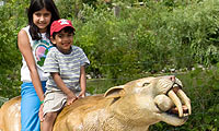 Children riding a play saber tooth tiger