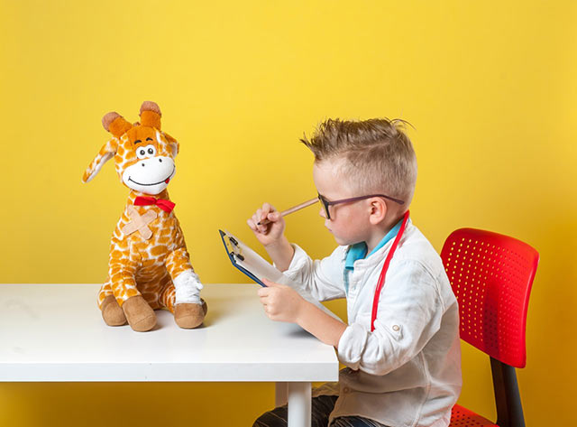 Boy sitting at table with stuffed bear